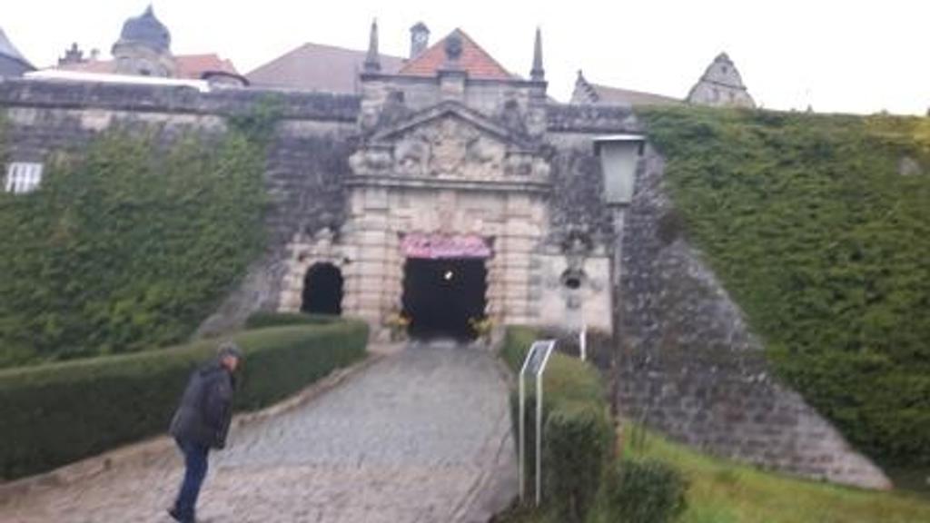 Ein Mann steht vor einem Burgtor.