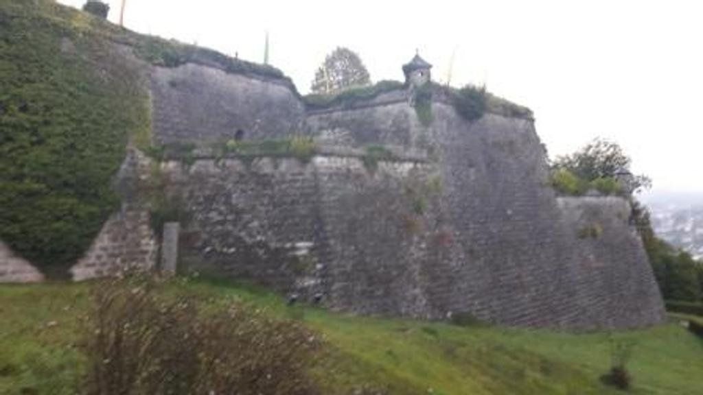 Auf einem grasbewachsenen Hügel steht eine große Steinmauer.