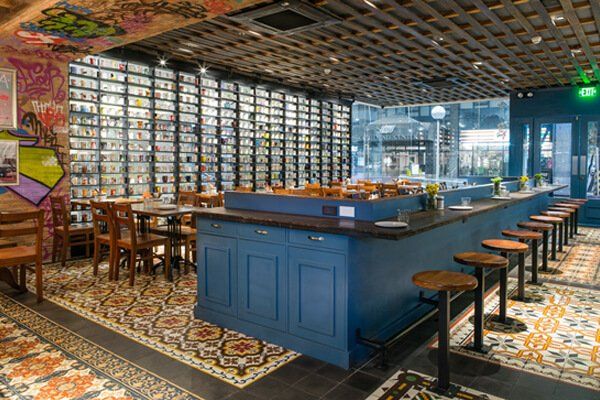 A restaurant with a long bar and tables and chairs.