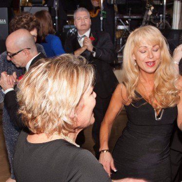 A woman in a black dress is dancing in a crowd