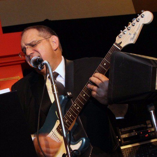 A man singing into a microphone while playing a guitar