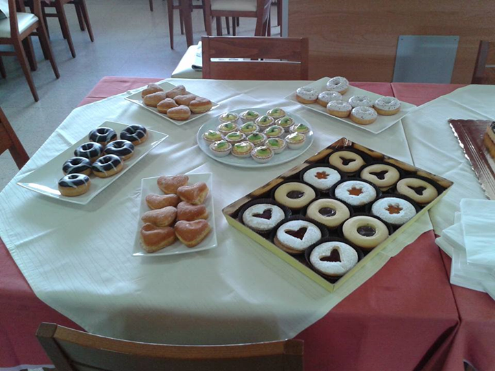 Tavolo apparecchiato con vari dolci, tra cui ciambelle, biscotti e altri piccoli dessert.