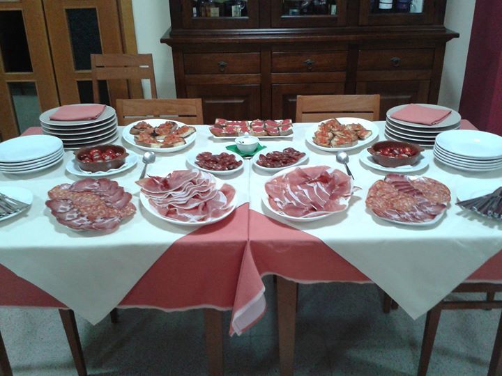 Un tavolo da pranzo apparecchiato con piatti di salumi e altre pietanze, pronti per il pasto.