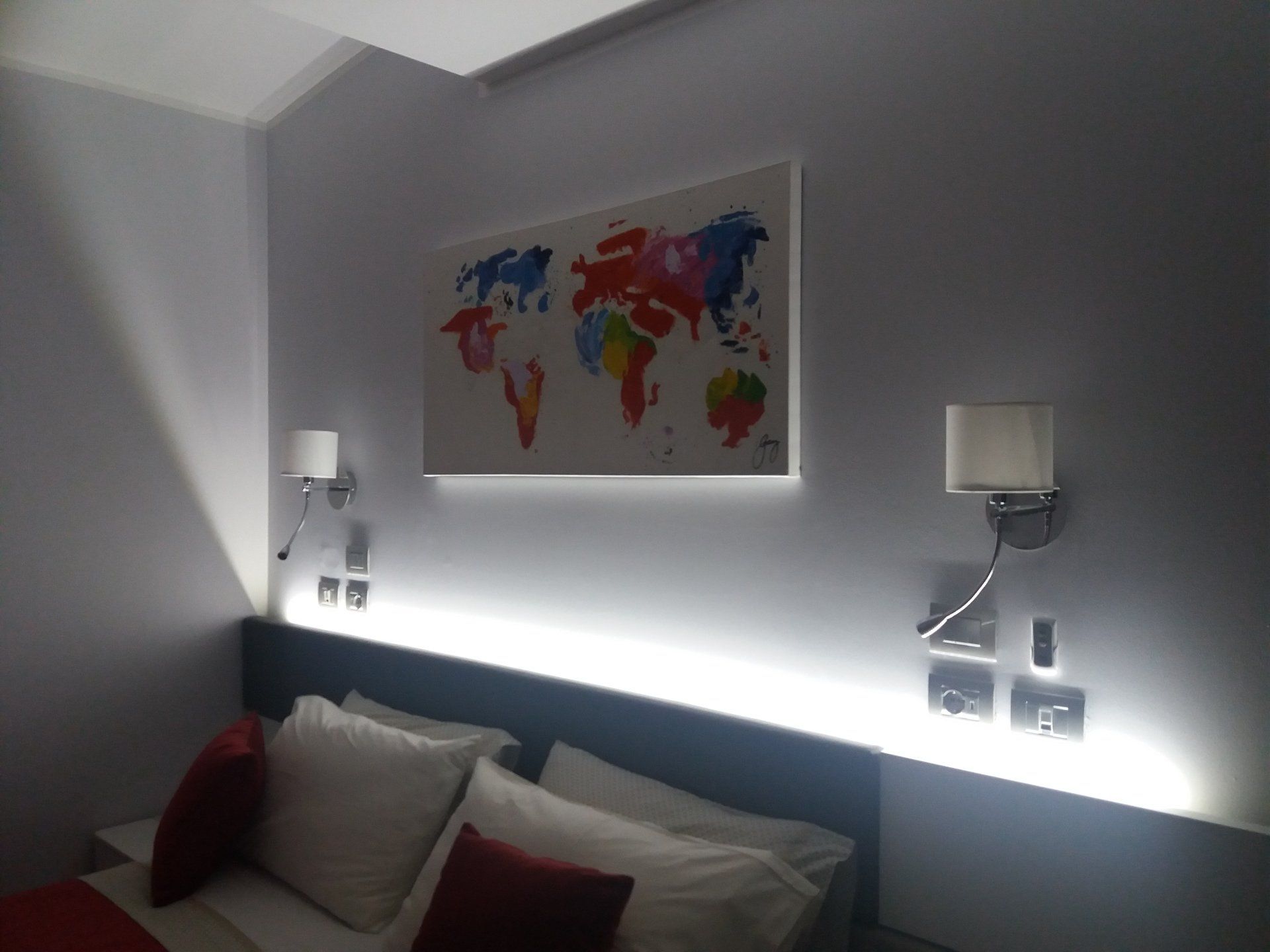 Camera da letto con letto, un colorato dipinto raffigurante una mappa del mondo e luci al neon.