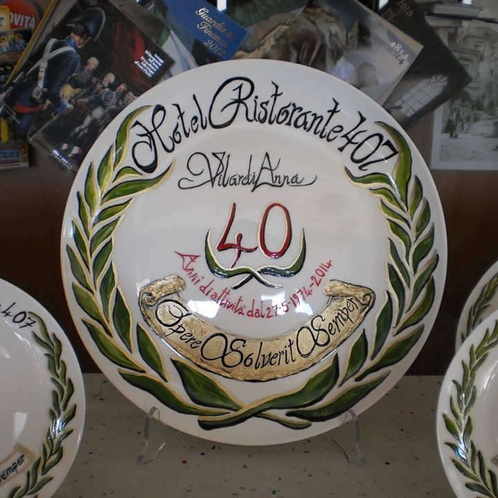 Piatto decorativo per l'Hotel Ristorante 407, che celebra i 40 anni. Presenta una bordura con rami d'ulivo e uno stendardo.