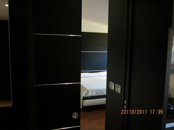 Le porte scorrevoli scure si aprono parzialmente per rivelare una camera da letto con un letto.