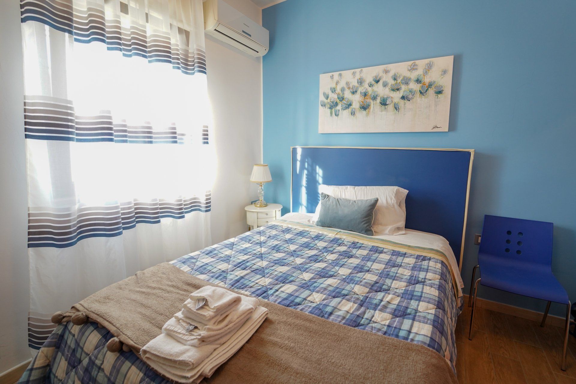 Camera da letto blu con letto singolo, biancheria da letto a quadri blu e bianchi e pareti blu.