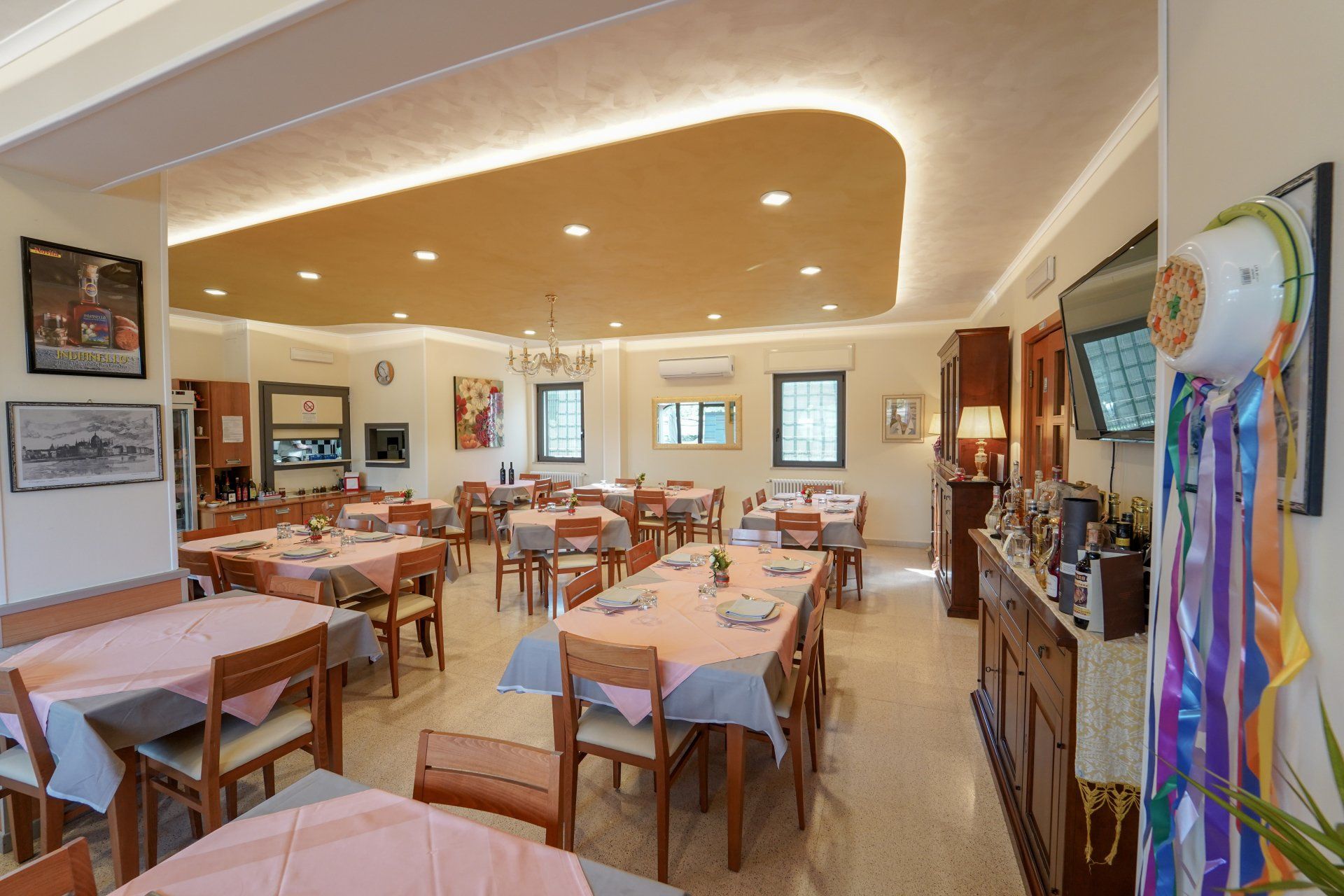 Sala da pranzo del ristorante con tavoli apparecchiati per il servizio, pareti beige neutre e illuminazione dall'alto.