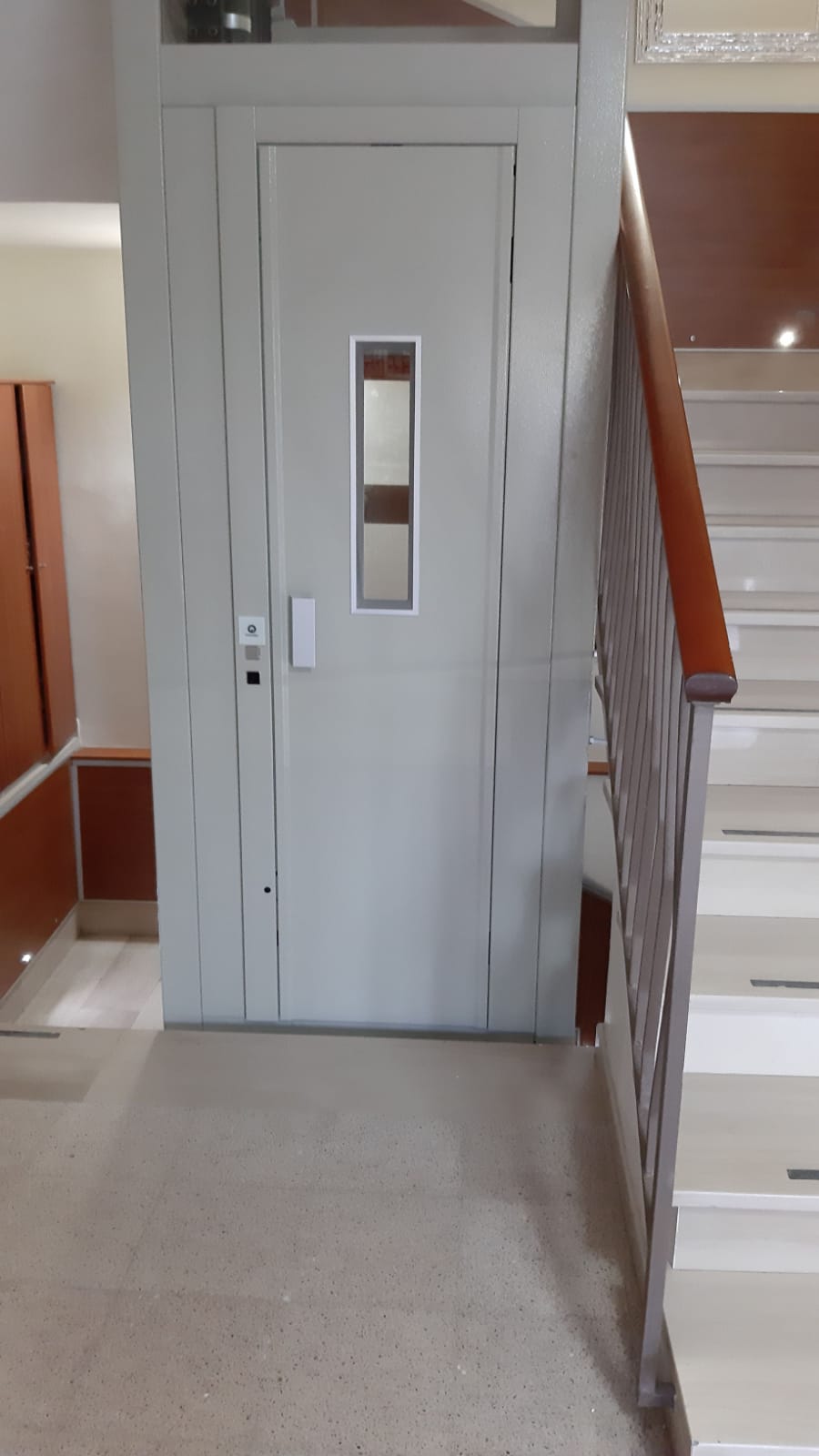 Una porta d'argento dell'ascensore con una piccola finestra accanto a una scala.