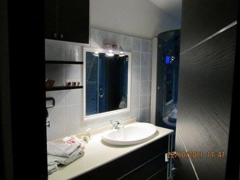 Bagno con lavandino bianco, specchio, doccia e mobili neri.
