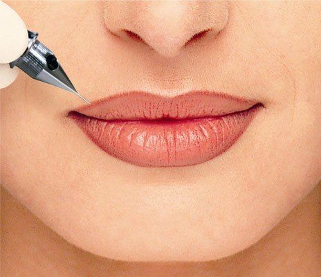 Eine Frau lässt sich mit einem Stift die Lippen tätowieren.