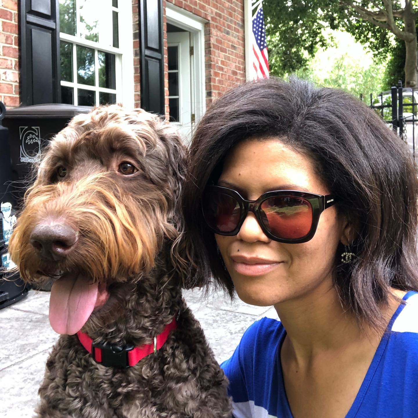 A woman wearing sunglasses is posing for a picture with her dog