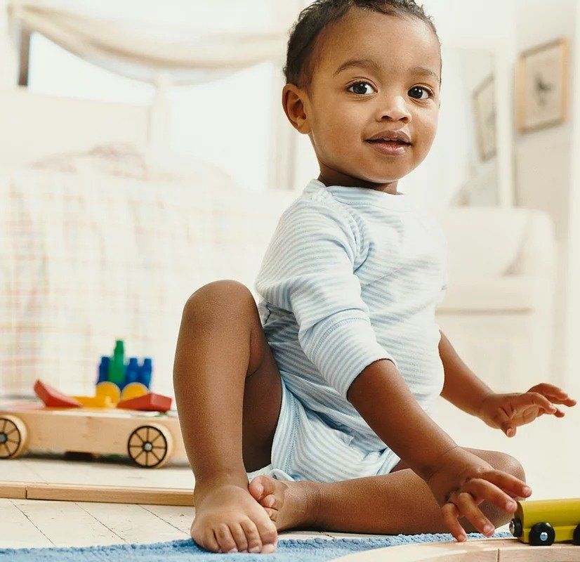 A baby is sitting on the floor playing with toys