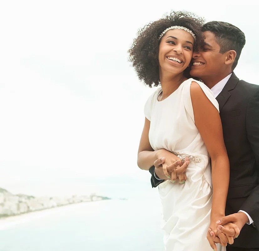 A bride and groom hold hands and smile for the camera