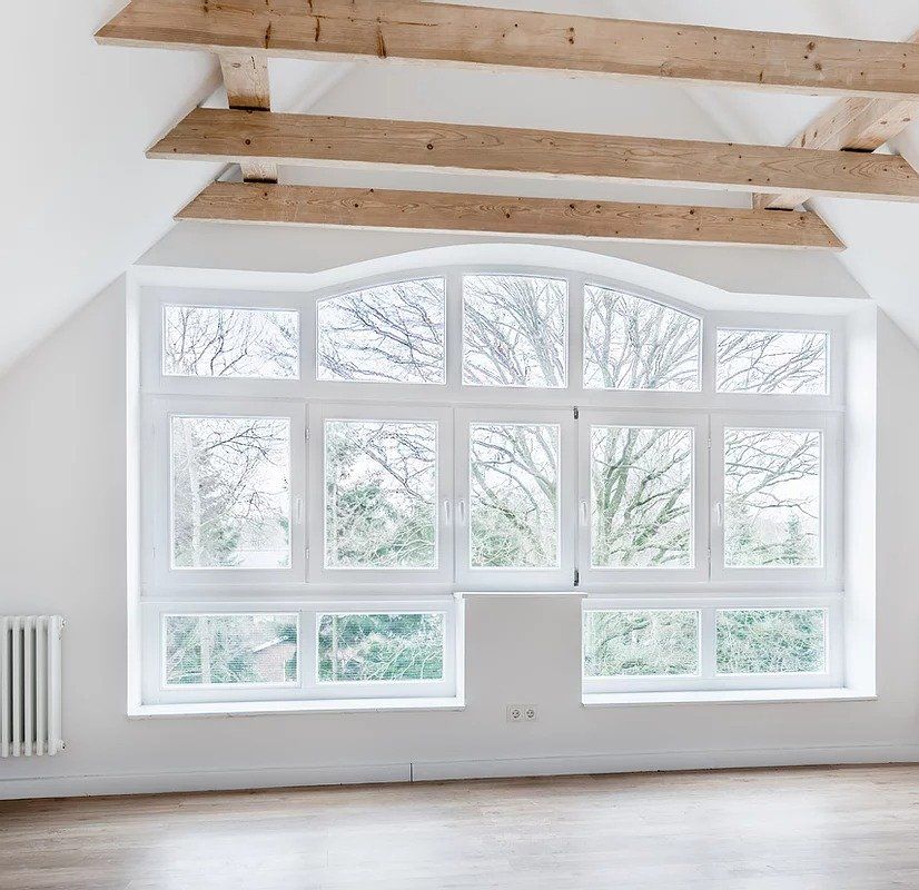 An empty room with a large window and wooden beams