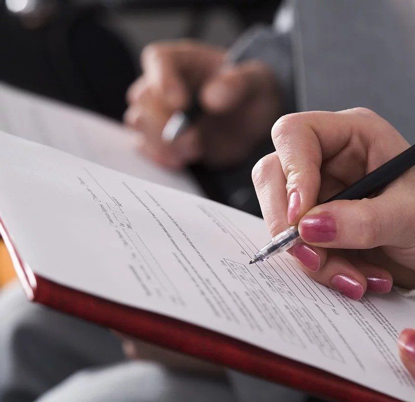 A woman is writing on a clipboard with a pen