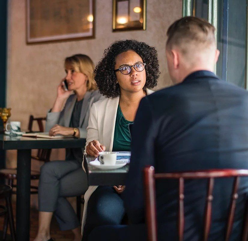 A man and a woman are sitting at a table in a restaurant having a conversation.