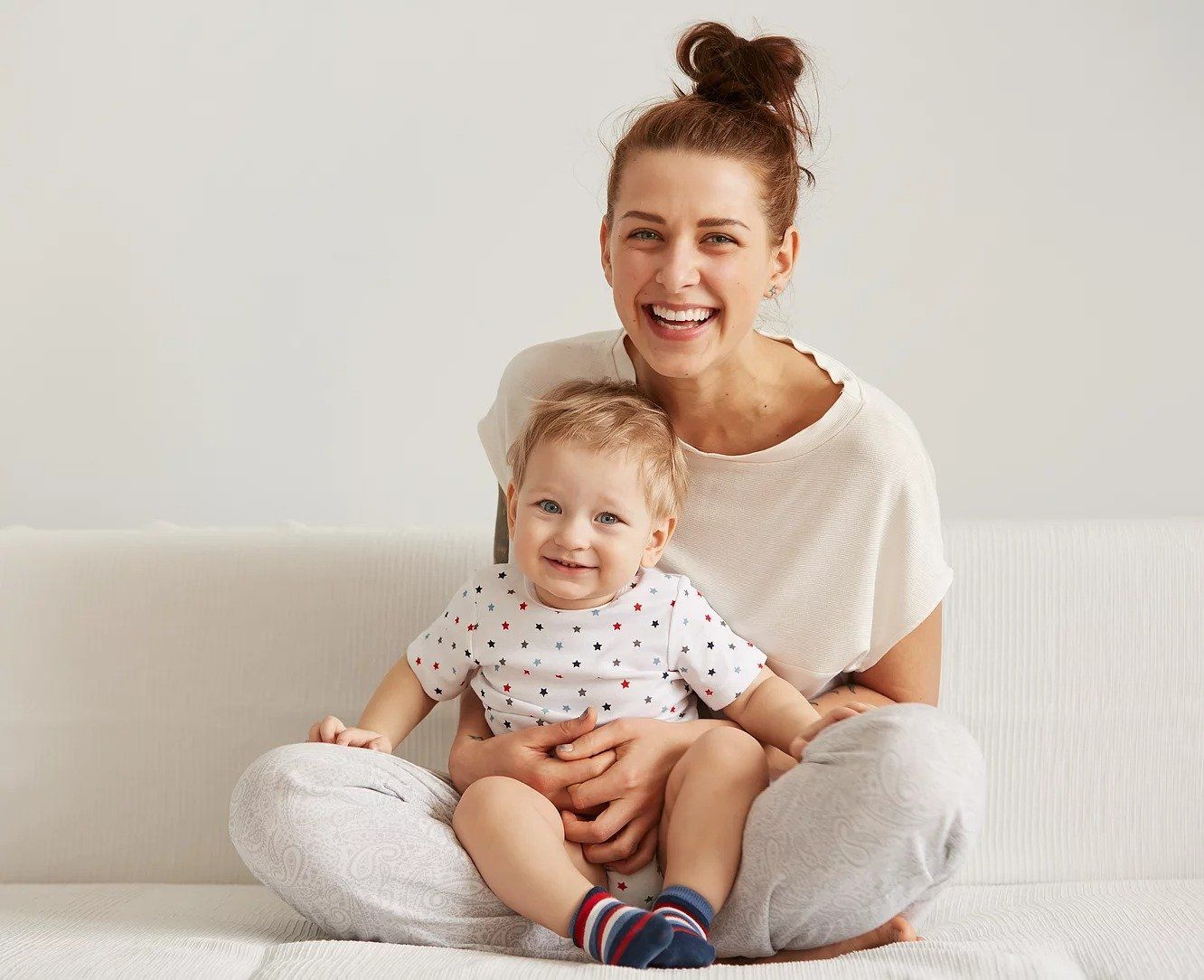 A woman is sitting on a couch holding a baby.