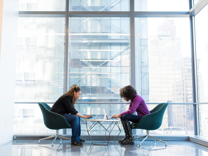 Two women are sitting at a table in front of a window.