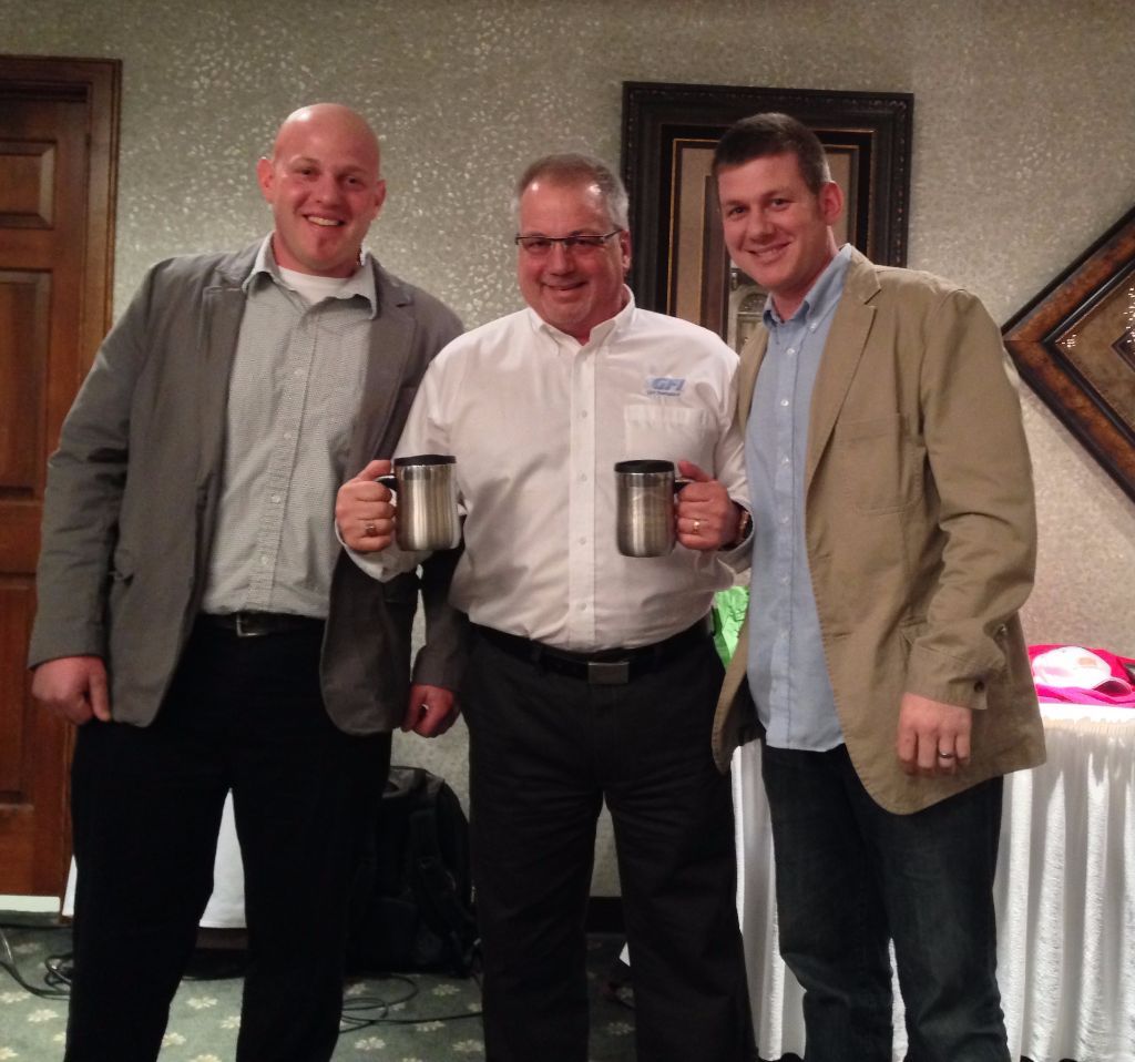 Three men standing next to each other holding mugs and smiling