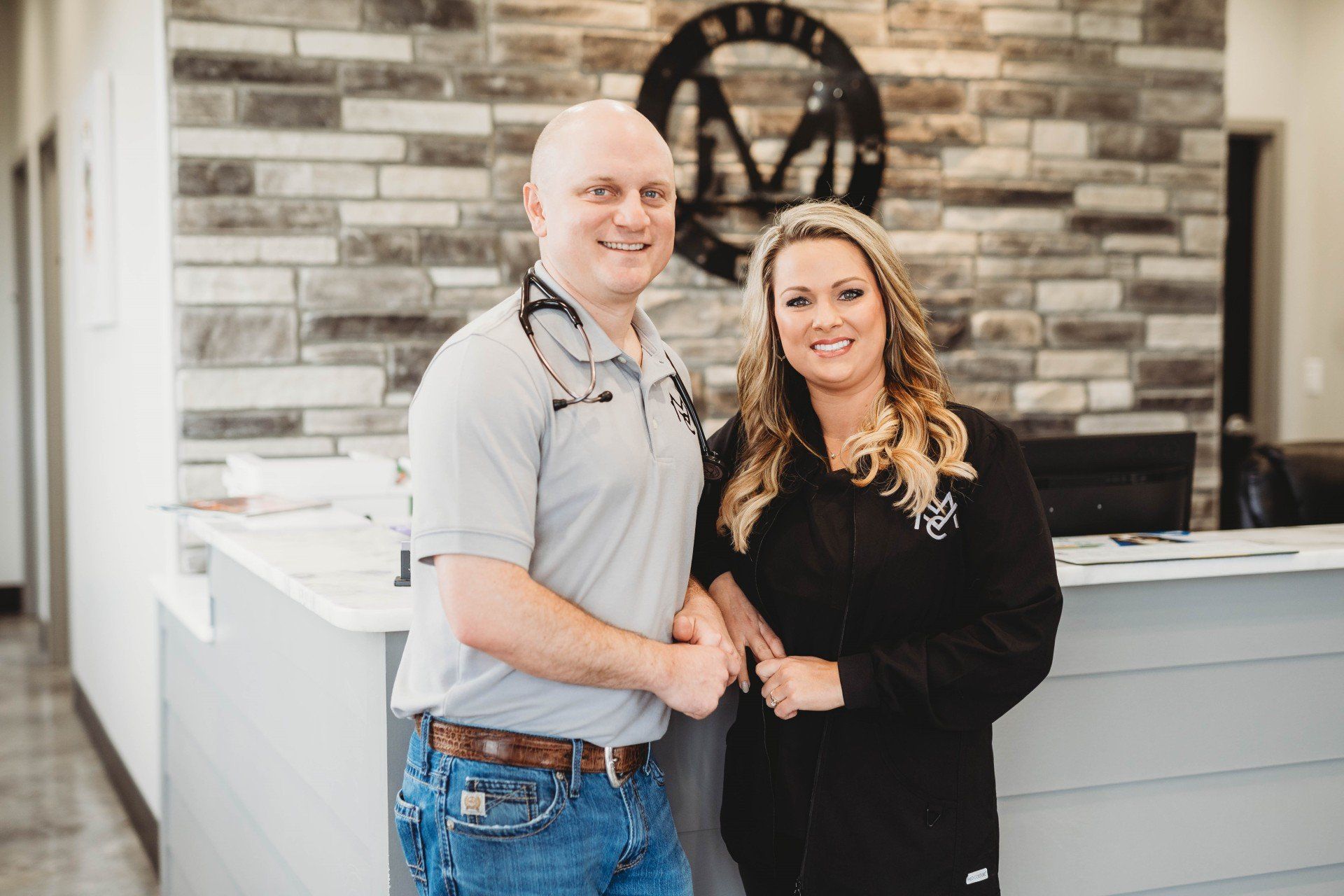 A man and a woman are posing for a picture in front of a brick wall.