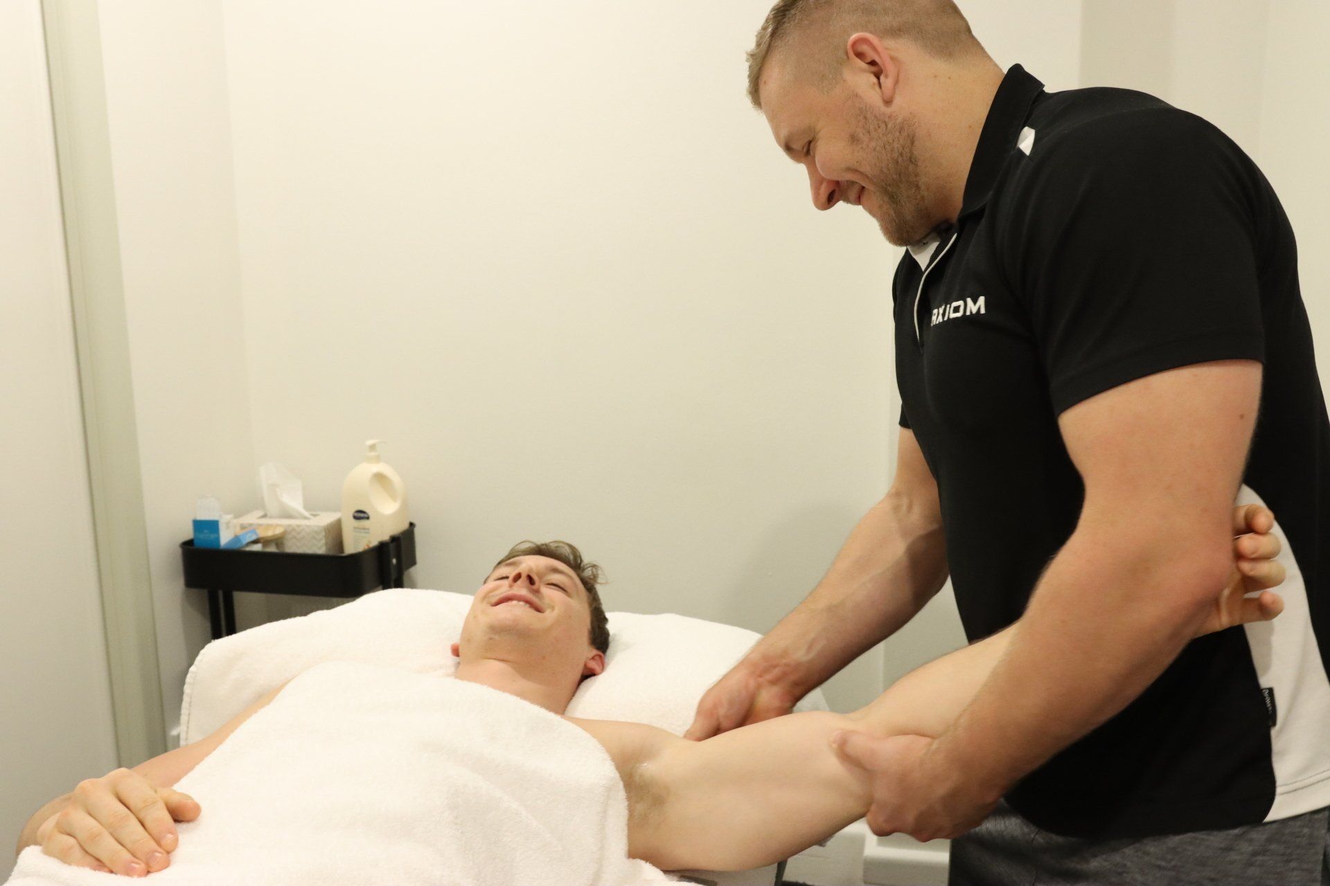 Man receiving arm massage from another man in a clinic.