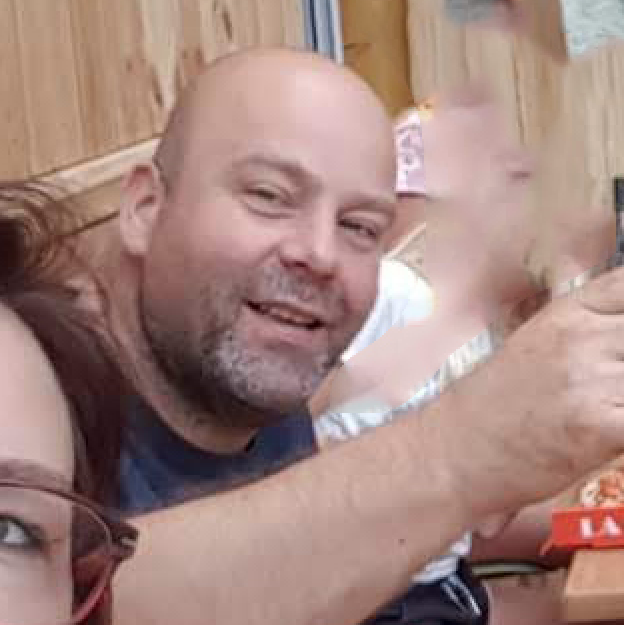 Een man en een vrouw zitten aan een tafel en houden een stuk papier vast.