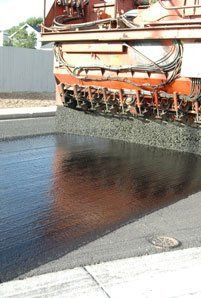 Chip Seal — Orange Truck Covering Wet Road in Denver, CO Chip Seal — Orange Truck Covering Wet Road in Denver, CO