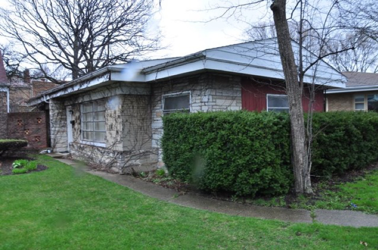 A small house with a hedge in front of it