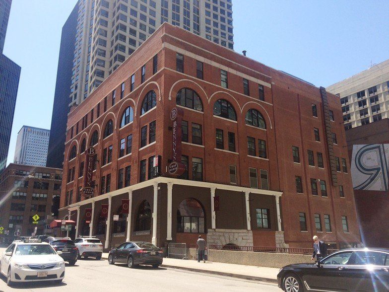 A brick building with cars parked in front of it in a city.