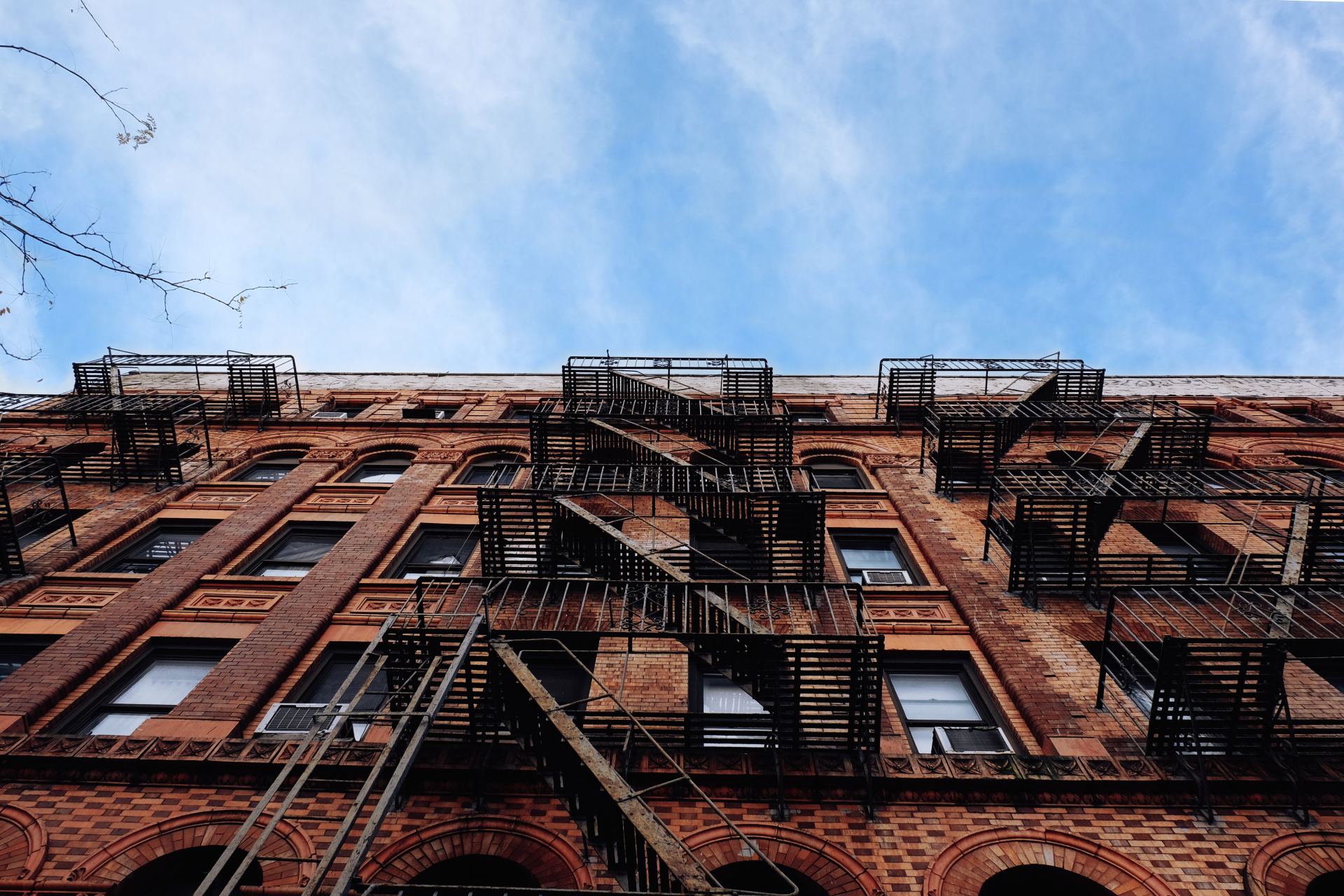 Looking up at a brick building with fire escapes