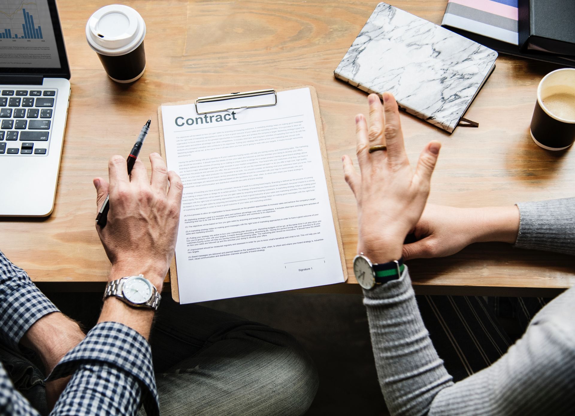 A man and a woman are sitting at a table looking at a contract.