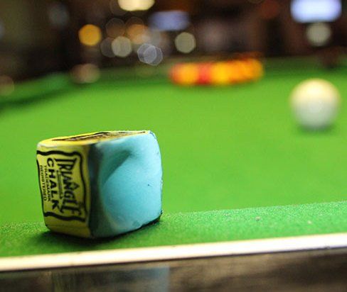man chalking a pool cue