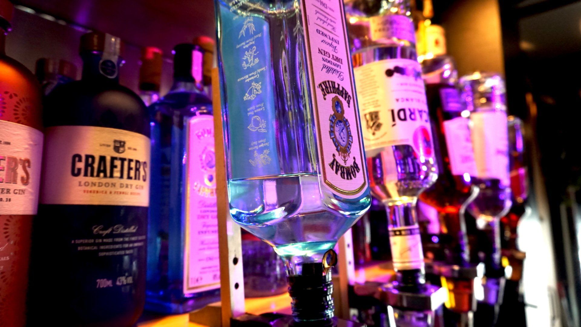 Een rij kleurrijke drankflessen op een barplank .