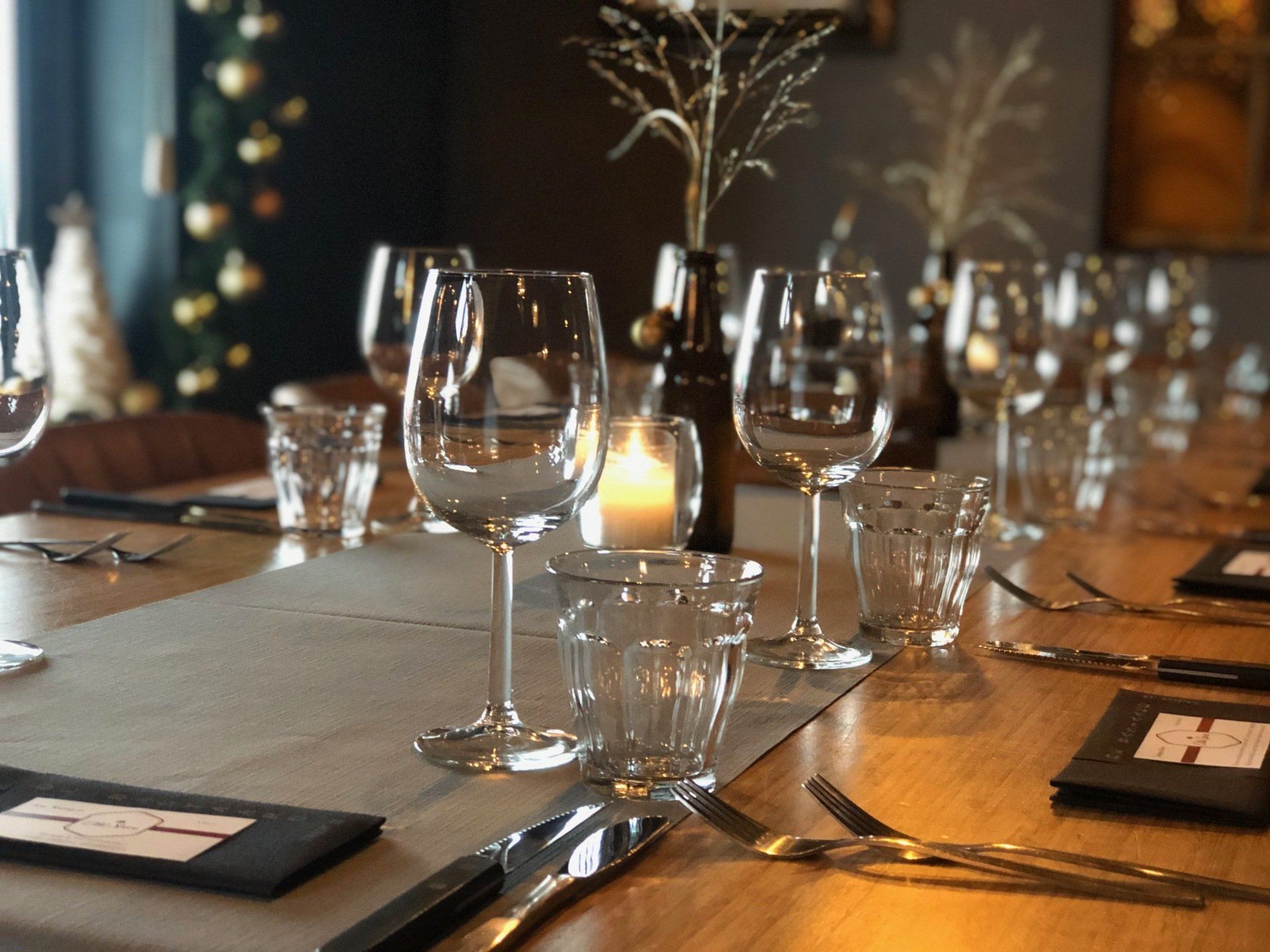 Een elegante eettafel, gedekt met wijnglazen, kaarsen en bestek, in een warme, schemerige kamer.