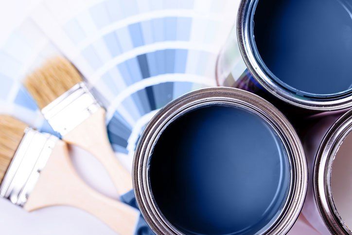 Paint brushes placed on top of can filled with blue paint
