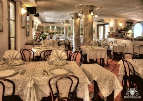 Dei tavoli apparecchiati e dei luci accesi all'interno di un ristorante