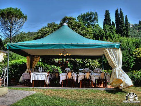 Dei tavoli apparecchiati sotto un gazebo