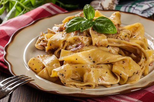 Un piatto di pappardelle e delle foglie di basilico