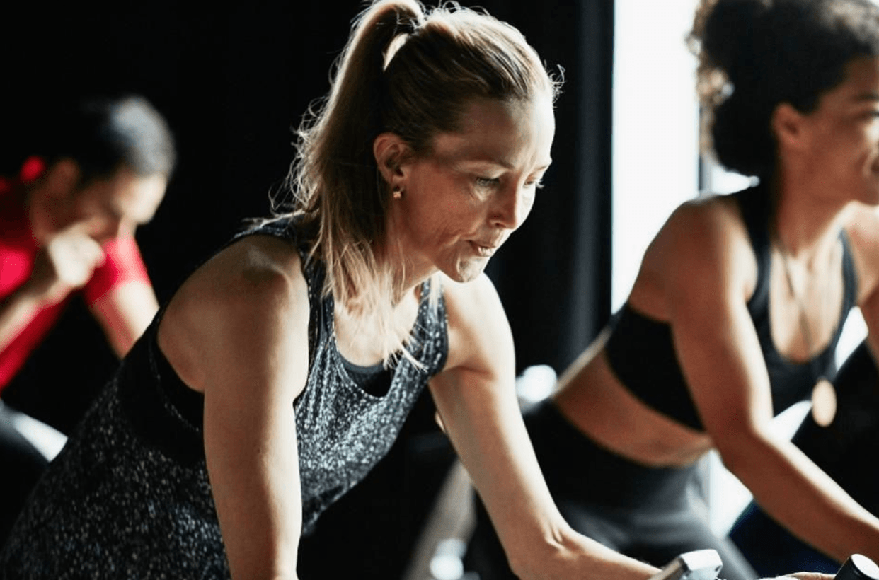 A group of women are riding exercise bikes in a gym.