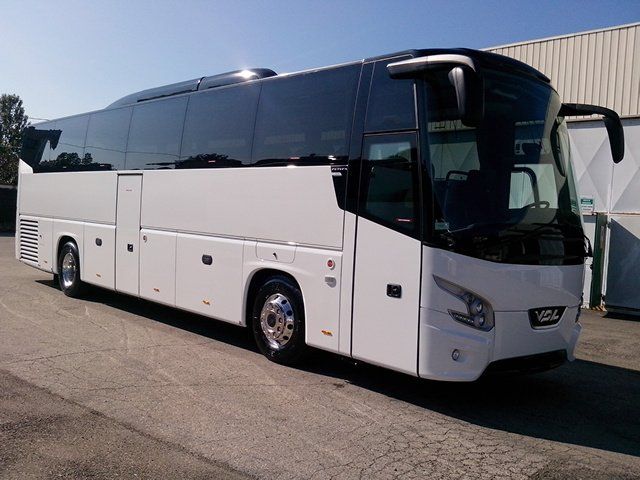 Pullman bianco con vetri oscurati parcheggiato sull'asfalto.