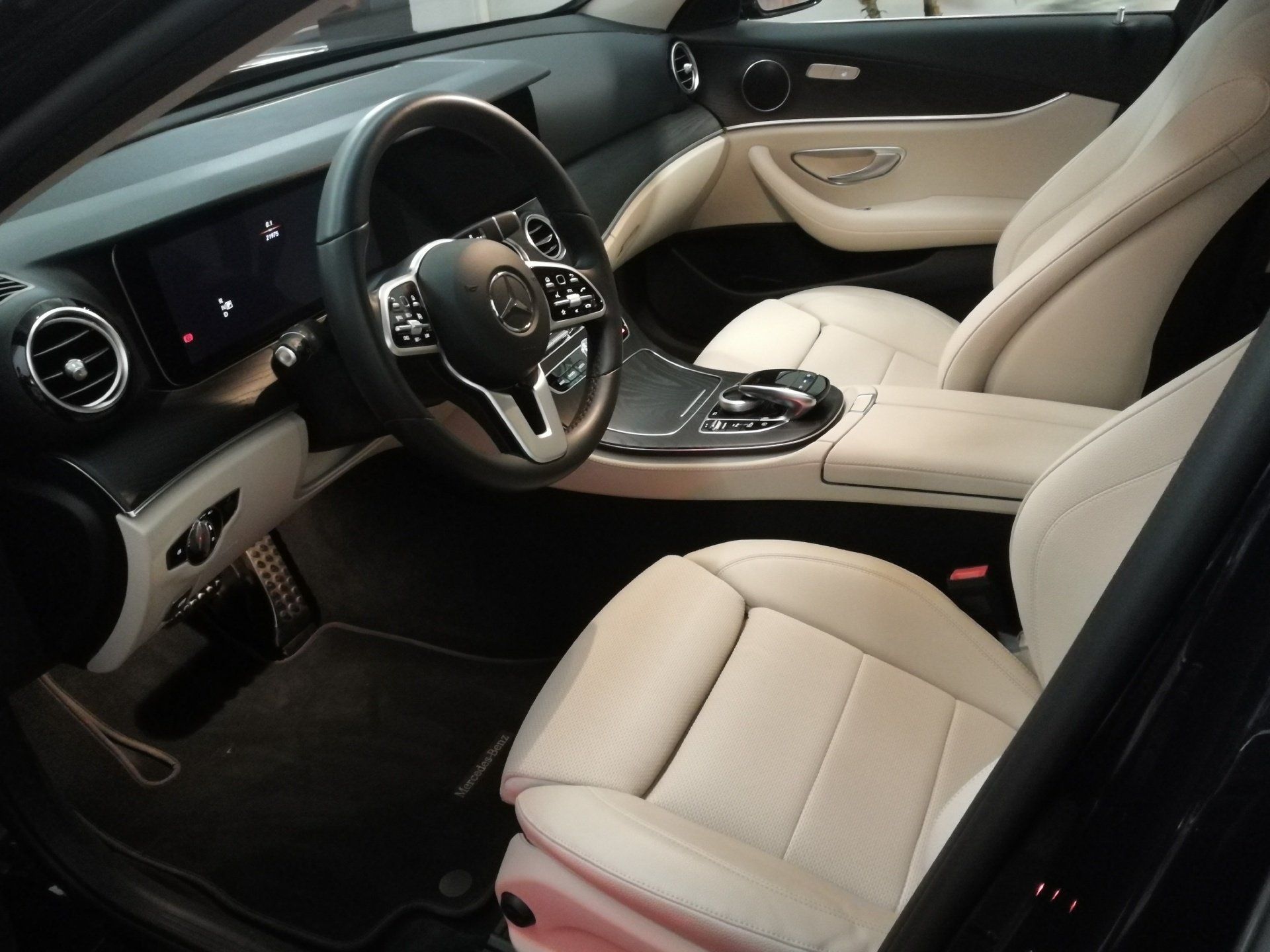Interno di un'auto Mercedes-Benz, con sedili in pelle beige e cruscotto nero.