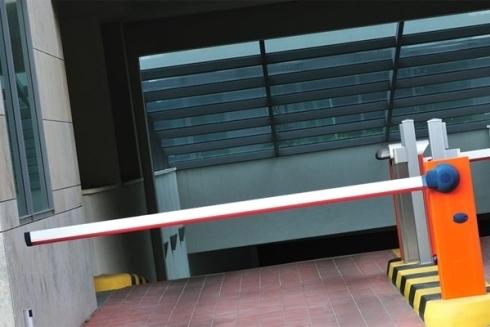 Barriera arancione e bianca che attraversa un vialetto piastrellato marrone e conduce a un edificio.