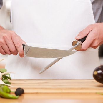 Sharpening Knife in Kitchen — Kansas City, MO — Ambrosi Bros. Cutlery Co Sharpening Knife in Kitchen — Kansas City, MO — Ambrosi Bros. Cutlery Co