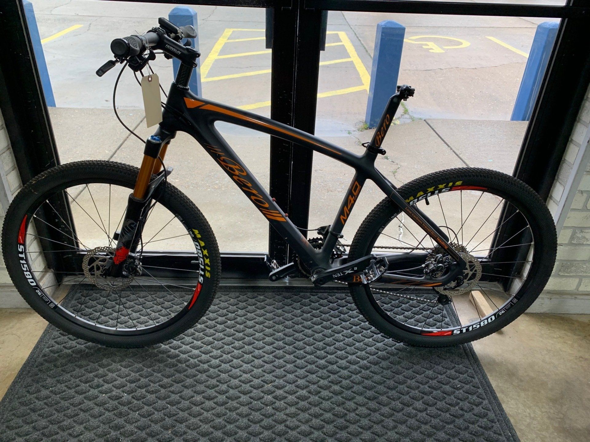 A bicycle is sitting on a mat in front of a glass door.
