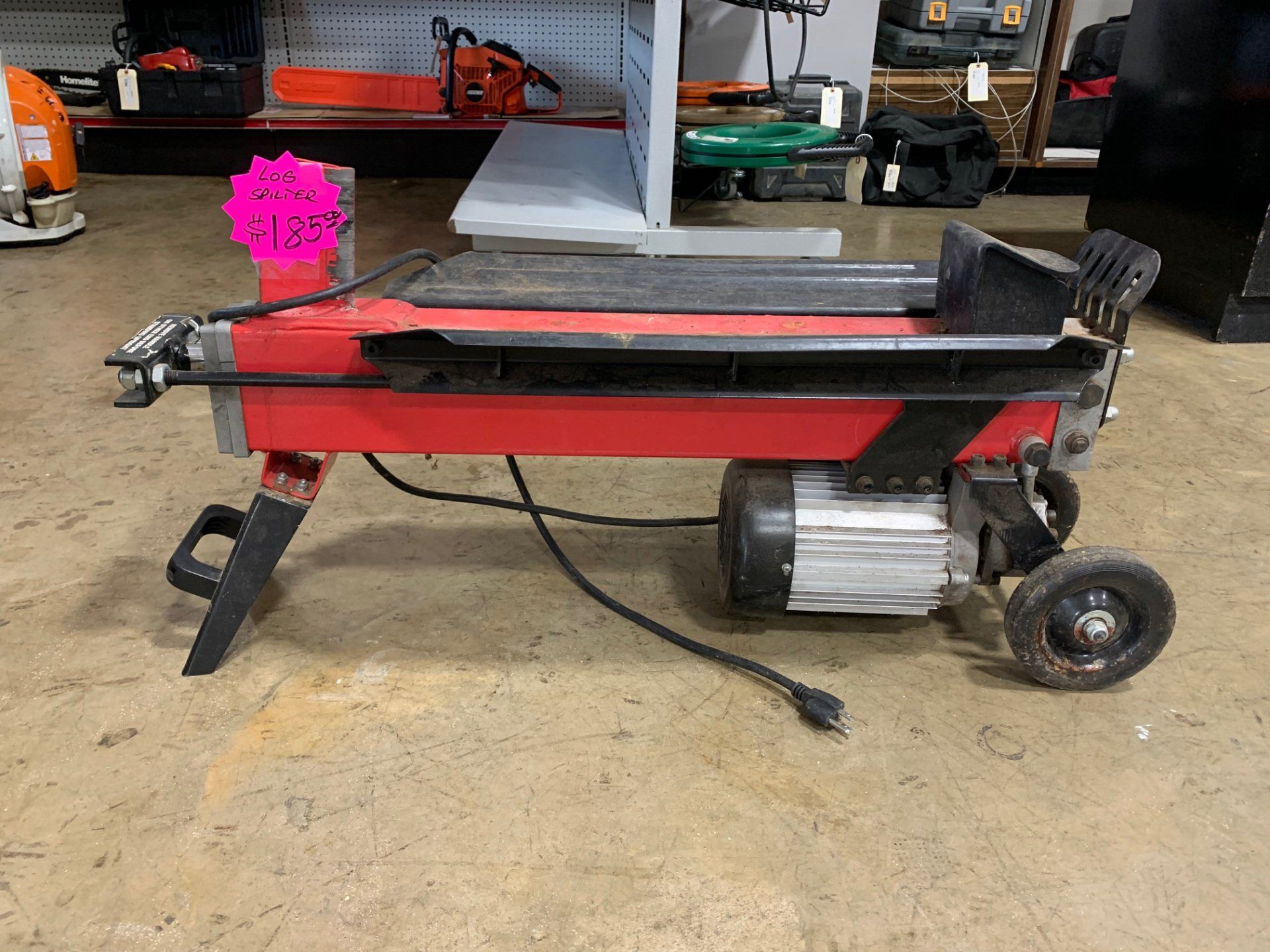 A red log splitter is sitting on the floor in a store.