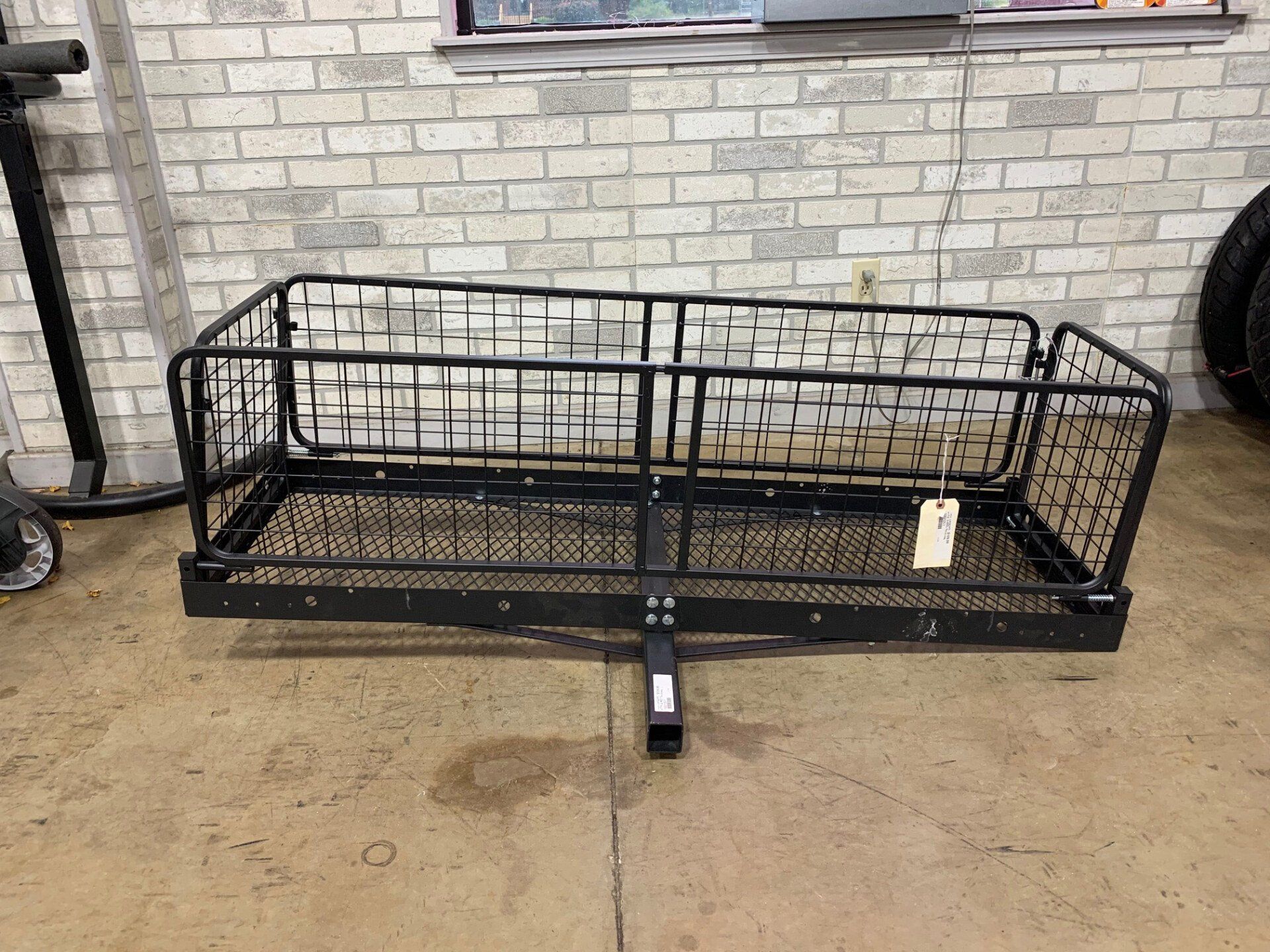 A cargo basket is sitting on the floor in front of a brick wall.