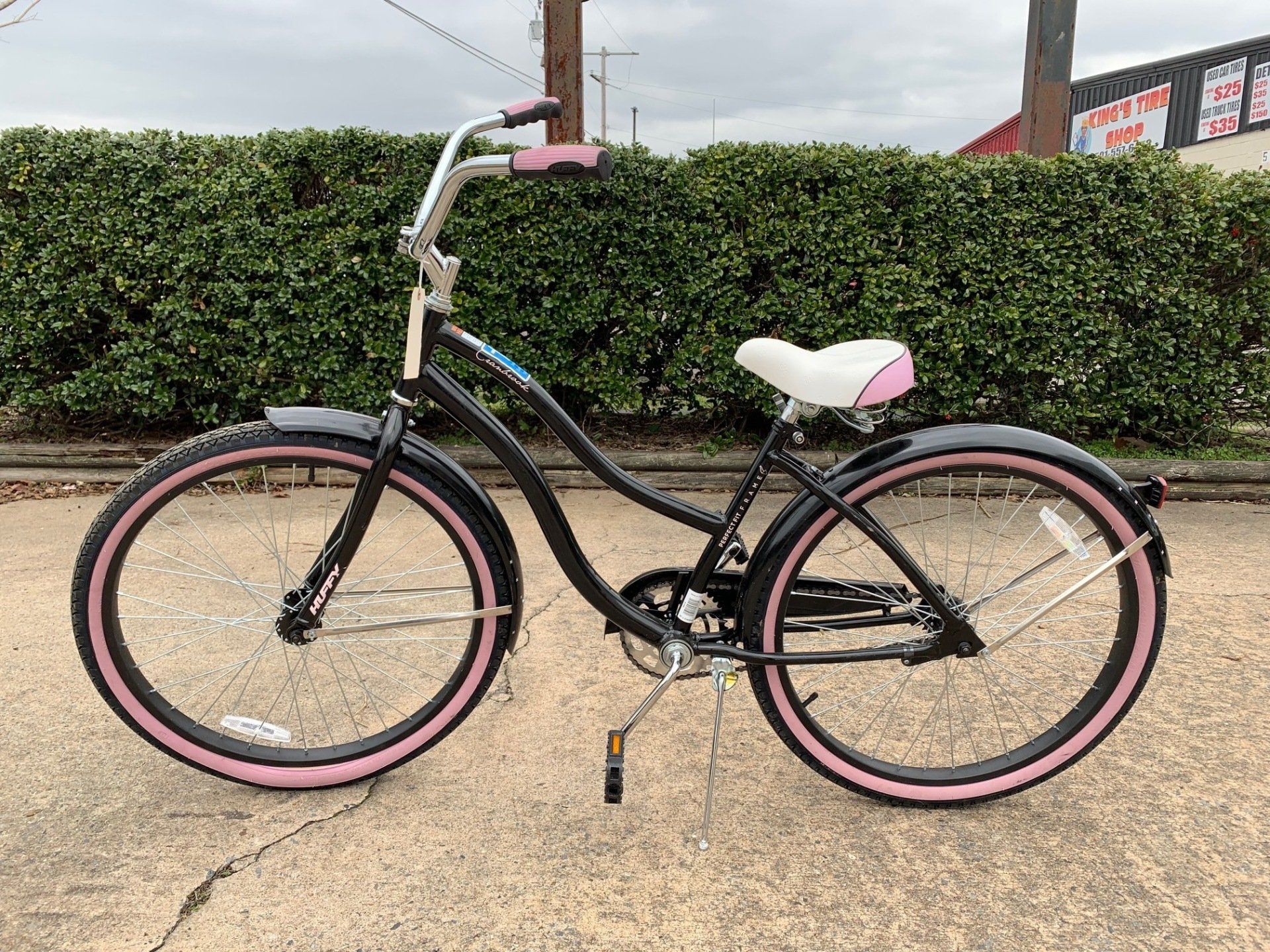 A black and pink bicycle is parked on the side of the road.
