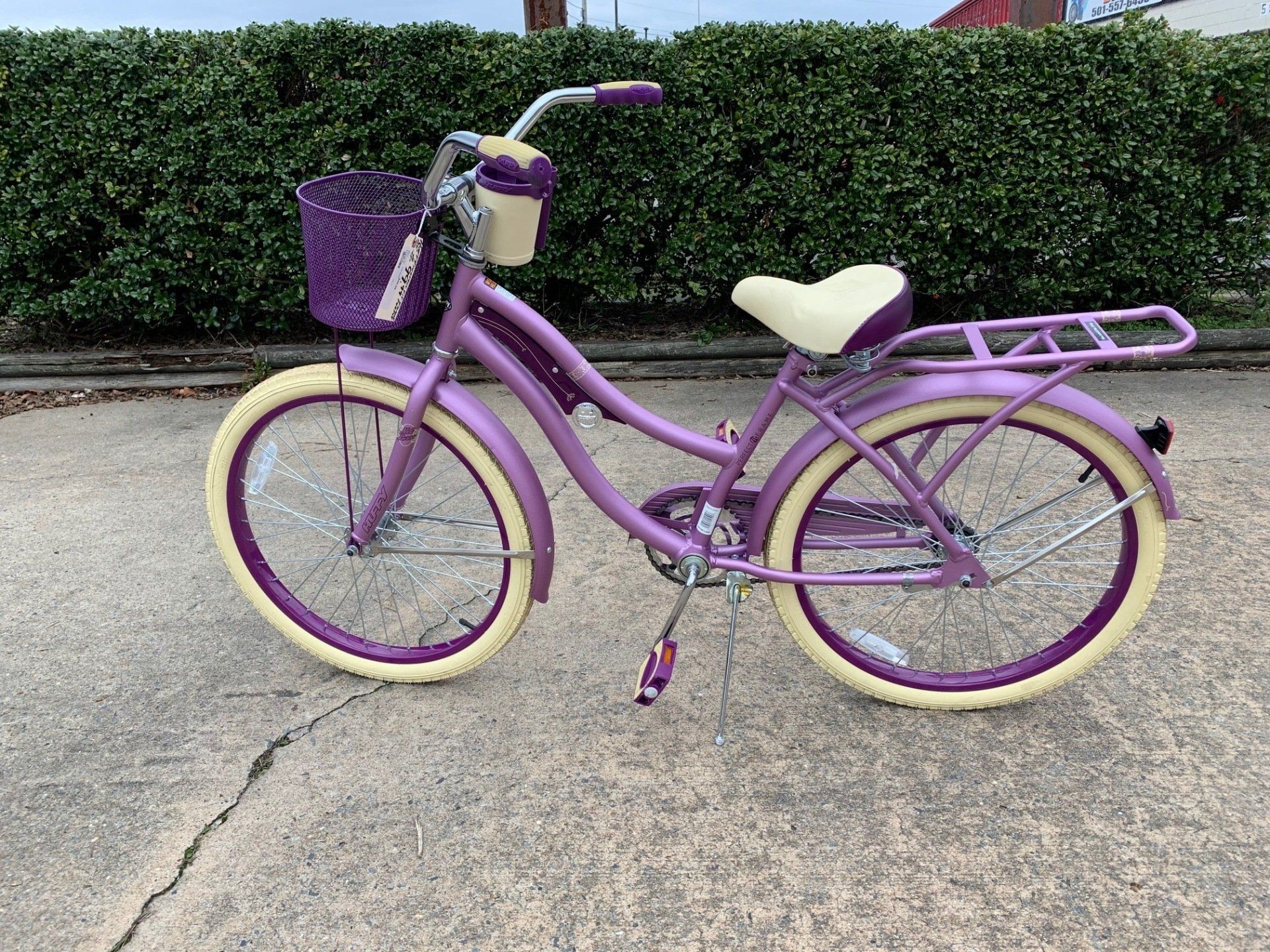 A purple bicycle with a basket on the front is parked on the sidewalk.
