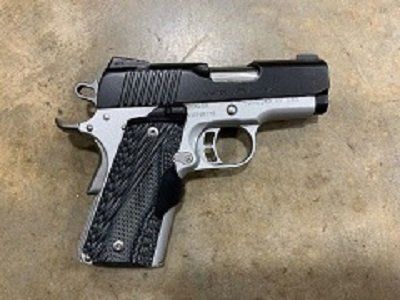 A black and silver handgun is sitting on a concrete surface.